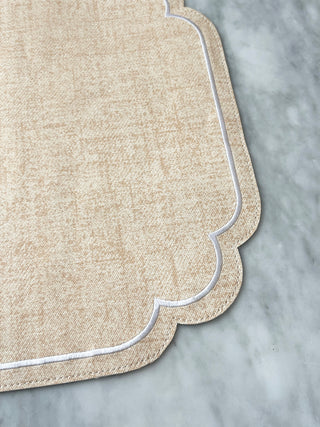 Coral tablemat with scalloped edge on a gray surface