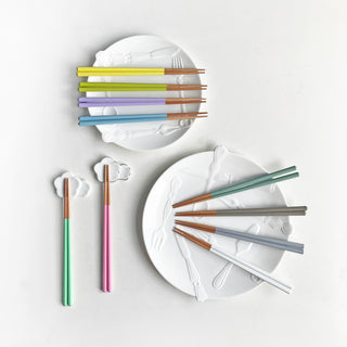 Set of colorful chopsticks on a white plate with a plain background