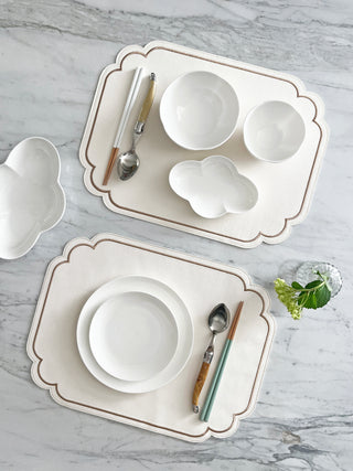 White ceramic dishes with decorative placemat on a marble surface