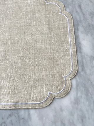 Textured beige placemat with scalloped edge on a gray surface