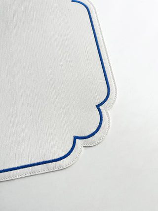 Ivory placemat with blue trim on a light gray background