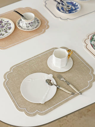 Set of placemats with cutlery and cups on a table